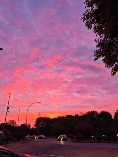 the sky is pink and purple as cars drive by