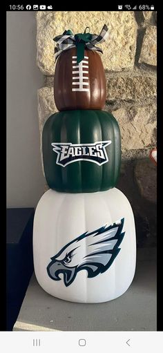 three football pumpkins stacked on top of each other with the philadelphia eagles logo painted on them