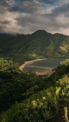 a scenic view of the ocean and mountains with clouds in the sky over it, as seen from an overlook point on a cloudy day