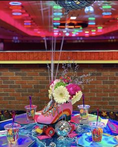 a party table with high heeled shoes and flowers on it, surrounded by confetti