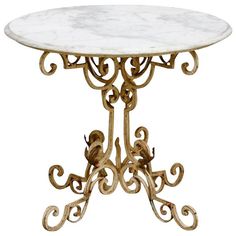 a marble topped table with metal legs and an ornate design on the top, against a white background