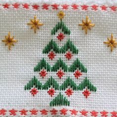 a cross - stitch christmas tree with red and green stars on it's side