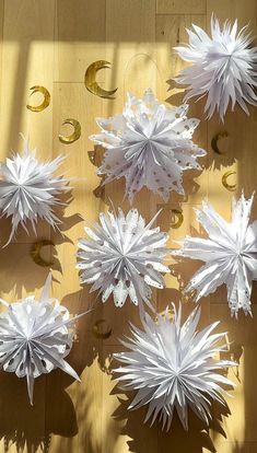 white paper snowflakes are arranged on a wooden surface with gold circles around them