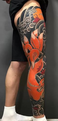 a man with an orange and black dragon tattoo on his leg