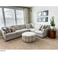 a living room with a large sectional couch and round coffee table in front of the window