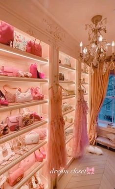 a room filled with lots of pink purses and handbags on shelves next to a chandelier