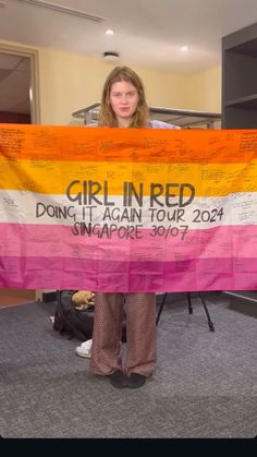 a woman holding up a pink, yellow and orange flag with writing on it that says girl in red