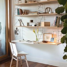 a white chair sitting in front of a shelf filled with books and other items on top of it