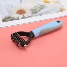 a blue and black hair clipper sitting on top of a pink table next to flowers