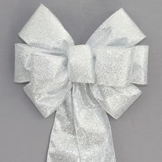 the large white bow is tied on top of a gray background with silver glitters