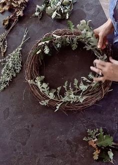 a man is making a wreath out of twigs and leaves on top of a table