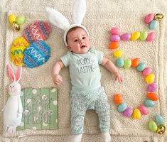 a baby is laying on a blanket with easter decorations around him and an assortment of candies