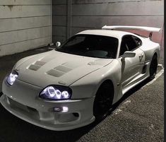 a white sports car parked in a parking lot next to a garage door at night