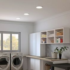 a washer and dryer sitting in a room next to a counter with plants