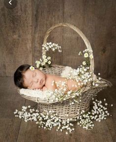 a baby is sleeping in a basket with flowers