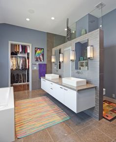 a large bathroom with two sinks and a bathtub in the center, along with an area rug on the floor