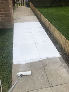 the sidewalk is being laid out in front of a brick building with grass and fence around it