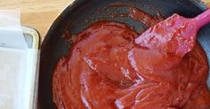 sauce in a pan with a pink spatula next to it on a wooden table