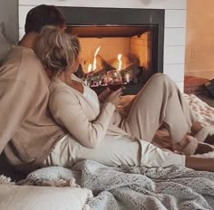 a man and woman sitting in front of a fireplace