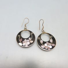 These hoop style, beautifully made black enamel and pink mother of pearl pierced earrings feature the incredible work of the Mexican metalsmiths. They are made of alpaca metal which looks like silver and wears like iron. The metal is an alloy with zinc, copper and tin. This pair is done with a floral design with pink mother of pearl, on a backdrop of black enamel. They are in excellent condition marked, Alpaca Mexico. The earrings measure 1 7/8ths inches high including the French hook fitting an Black Enamel Hoop Earrings As Gift, Black Enamel Hoop Earrings For Gift, Dainty Hoop Earrings, Earrings Black, Brass Earrings, Pierced Earrings, Jewelry Earrings Hoops, Vintage Costume Jewelry, Silver Hoops