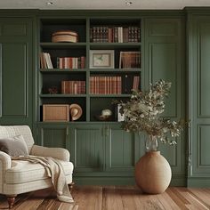 a living room filled with green bookshelves next to a white chair and wooden floor