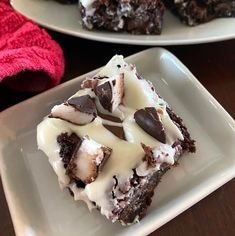 two white plates topped with brownies covered in frosting and marshmallows