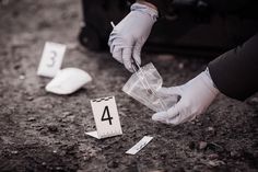 a person in white gloves placing numbered numbers on the ground