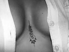 a black and white photo of a woman's breast with an arrow tattoo on it