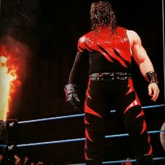 a wrestler standing in front of a fire