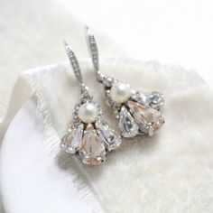 Elegant & full of shimmer, our delicate Antique gold Austrian crystal drop Bridal earrings are perfect for any special occasion. - Handcrafted with Austrian crystals and pearls- Each stone is set by hand in my studio- Golden shadow and clear stones with cream pearl accents- Antique gold finish- Earring wire is studded with cz stones- Earrings measure 1.5 inches x 1/2 inch- Handcrafted in the US.- Nickel free and hypoallergenicPLEASE ALLOW APPROX 10 BUSINESS FOR COMPLETION BEFORE SHIPPINGThis is Drop Bridal Earrings, Stones Earrings, Golden Shadow, Bridal Earrings Drop, Earring Wire, Pearl Cream, Clear Stone, Crystal Drop, Austrian Crystal