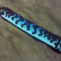 a blue and black beaded keychain sitting on top of a brown blanket