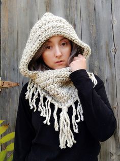 a woman wearing a hat and scarf while talking on a cell phone in front of a wooden fence