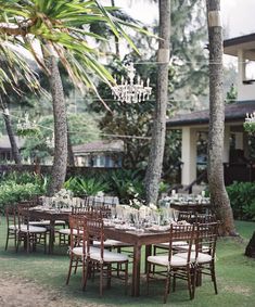 an outdoor dining table set up with chairs and chandelier