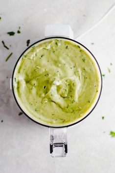 an overhead view of a blender filled with guacamole and garnish