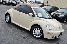 a beige car parked in a parking lot next to other cars