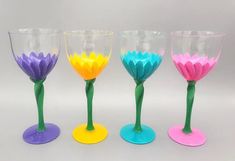 three wine glasses with different colored flowers in them