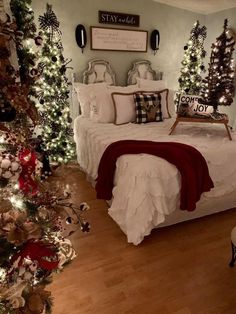 a bedroom decorated for christmas with white bedding and red throw pillows, tree decorations