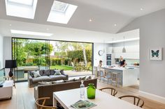 an open concept kitchen and living room with skylights on the ceiling, two people in the background