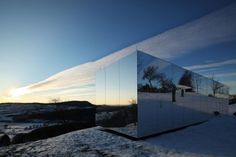 a large mirrored building sitting on top of a snow covered field