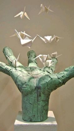 a sculpture with origami birds flying over it's head and arms in the air