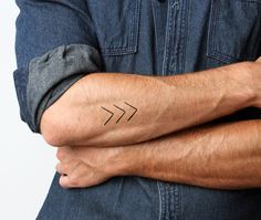 a man's arm with a small arrow tattoo on the left side of his arm