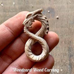 a hand holding a wooden carved ring with a dragon on it's side and the words woodard wood carving