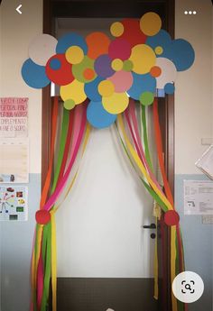 a bunch of balloons that are on top of a door frame with ribbons and streamers