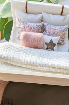 a bed with pillows and blankets on top of it next to a potted plant