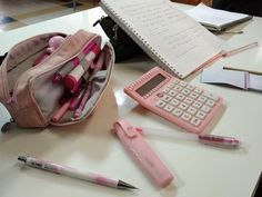 a pink school bag sitting on top of a table next to a calculator