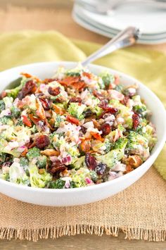 a white bowl filled with broccoli salad on top of a yellow napkin next to a fork