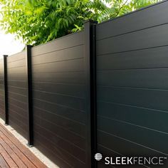 a black fence is next to a wooden deck and trees on the side of it