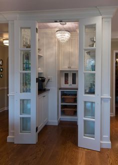 an empty kitchen with white cabinets and wood flooring, is seen from the doorway