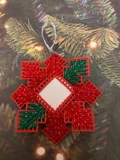 a red and green ornament hanging from a christmas tree