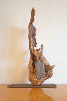 a piece of driftwood sitting on top of a wooden table next to a white wall